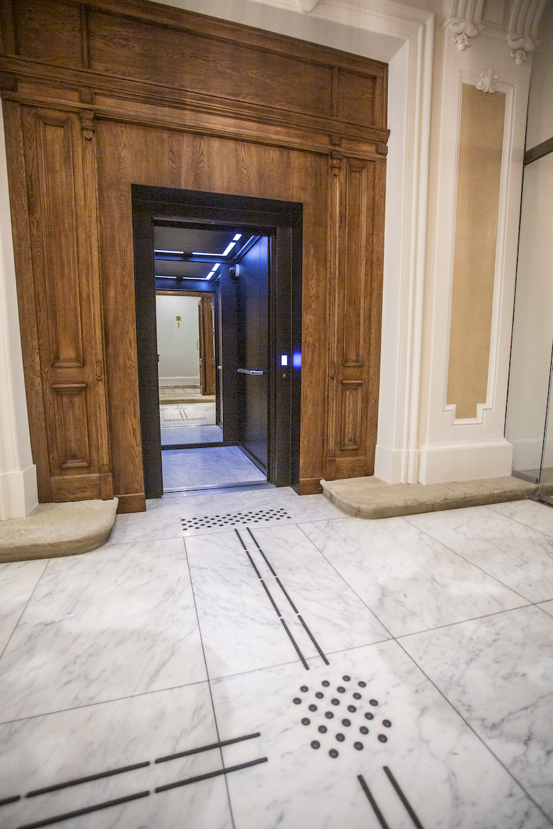 Otwarta winda. Do windy kierują ścieżki dotykowe na podłodze.