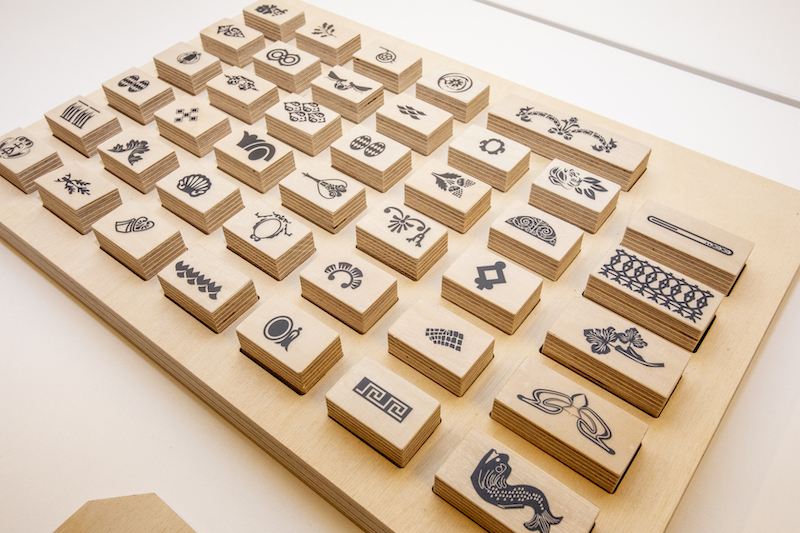 Drewniana plansza z wypukłymi, ruchomymi kostkami. Na każdej z nich narysowany element dekoracyjny budynku.