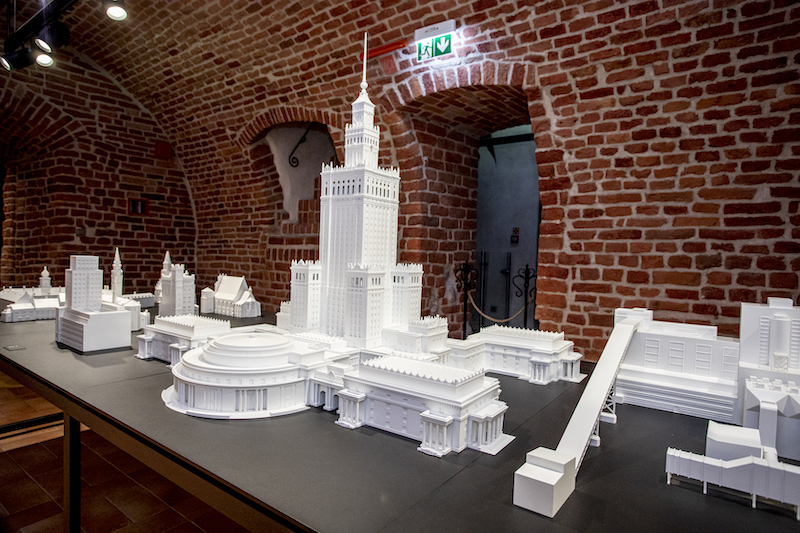 Na stole kilkanaście wydruków 3D najważniejszych budynków Warszawy. Wśród nich góruje ponad metrowy model Pałacu Kultury i Nauki.