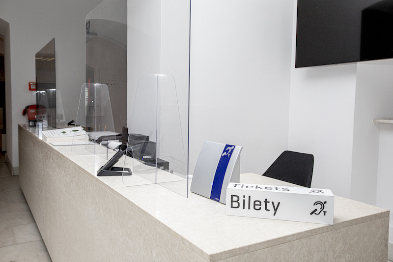 Lada punktu informacyjnego. Na ladzie tabliczka z napisem „Bilety” i symbolem pętli indukcyjnej. Obok druga tabliczka z granatowym piktogramem pętli indukcyjnej.